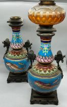 A pair of china oil lamps with fish decoration to centre and metal handles depicting butterflies,