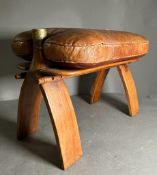 A middle Eastern camel stool with brown leather seat on a hardwood and brass frame