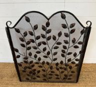 A wrought iron and wire mesh fire guard with leaf details