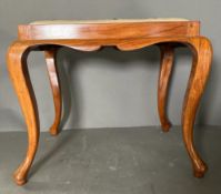 A wooden framed piano stool with a scrolling upholstered seat