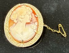 A 9ct gold cameo brooch of a lady in a classical pose with a safety chain