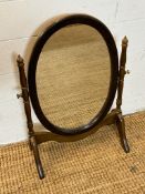 An oval framed bathroom mirror on splayed feet