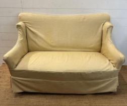 A two seater cream upholstered skirted sofa