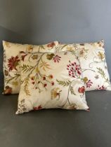Three cream ground floral cushions