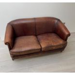 A two seater leather sofa, with tapering legs and a dark tan piping to edge (H77cm W144cm D70cm