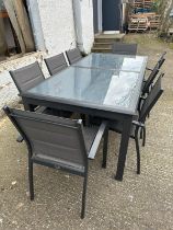 A contemporary grey metal garden table with two piece glass top and eight garden chairs by Alice’s