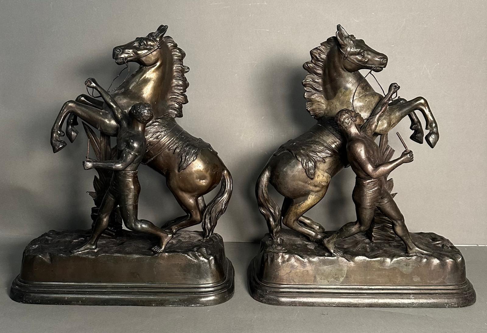 A pair of metal sculpture of tribal figures wrangling rearing horses Height approximately 40cm