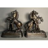 A pair of metal sculpture of tribal figures wrangling rearing horses Height approximately 40cm