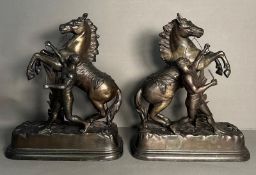A pair of metal sculpture of tribal figures wrangling rearing horses Height approximately 40cm