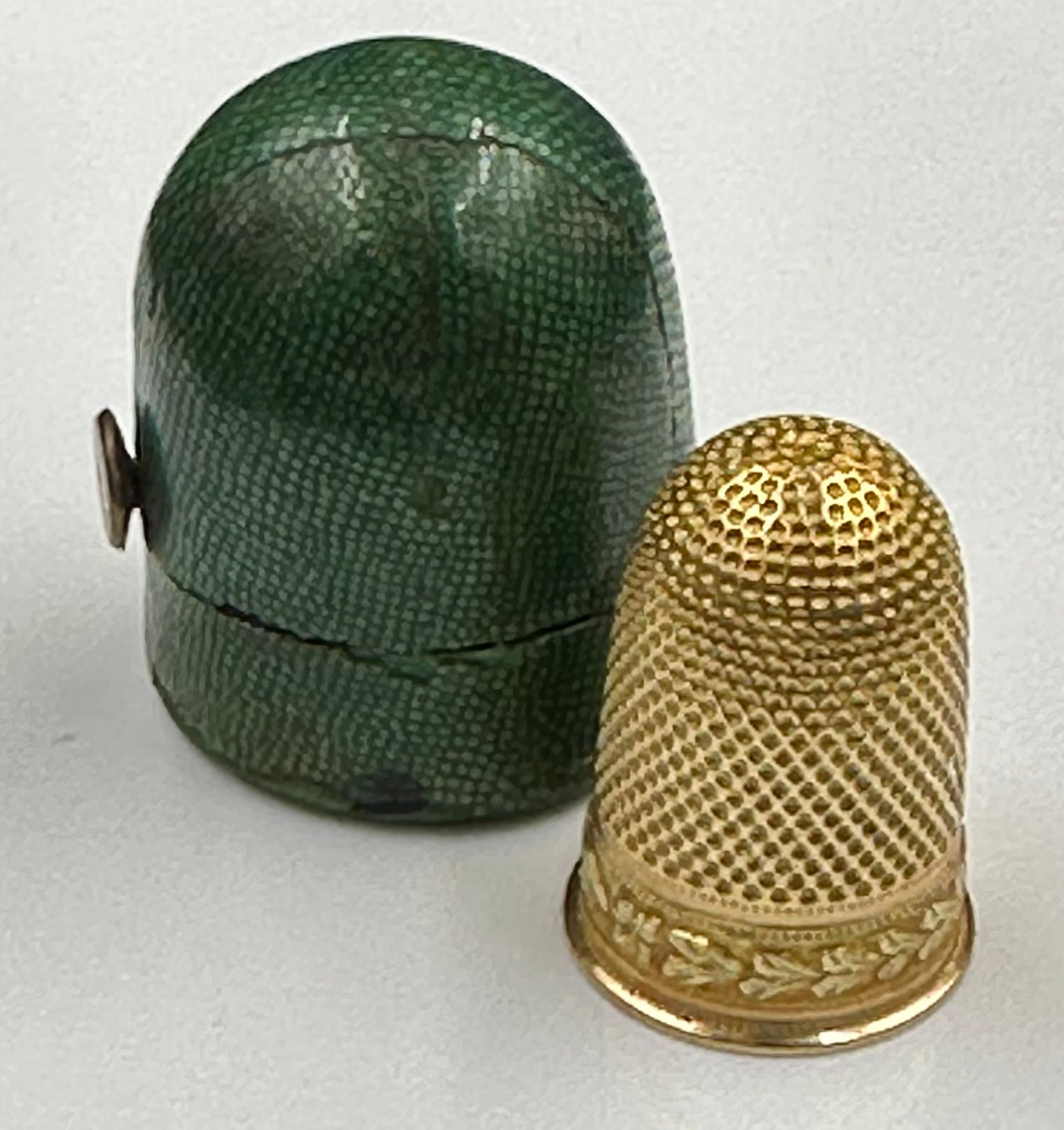 A gold thimble, approximately 4.4g, in a green shagreen holder.