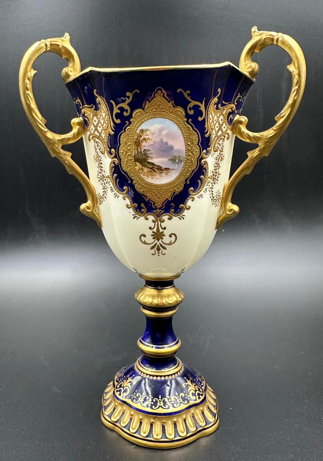 An early 20th Century Coalport, three handled goblet with blue grounds under a acid etch gilt