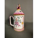 A French lidded mug decorated in pinks and yellows with floral central shield