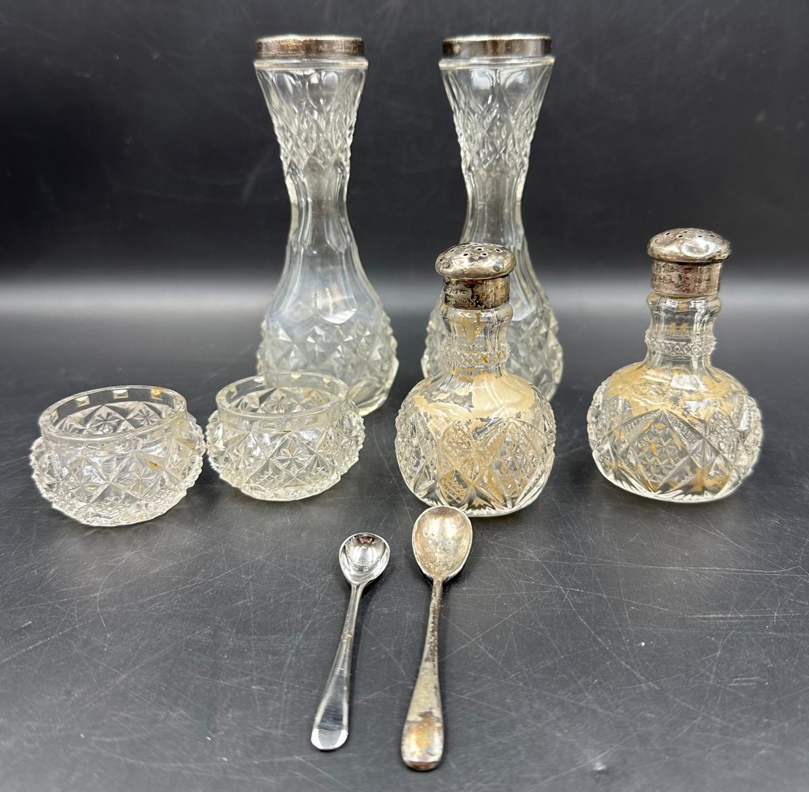 A selection of cut glass cruets with silver tops, hallmarked for Chester and two silver topped