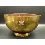 An antique brass bowl with four floral decorations, 21.5cm across and 12cm H