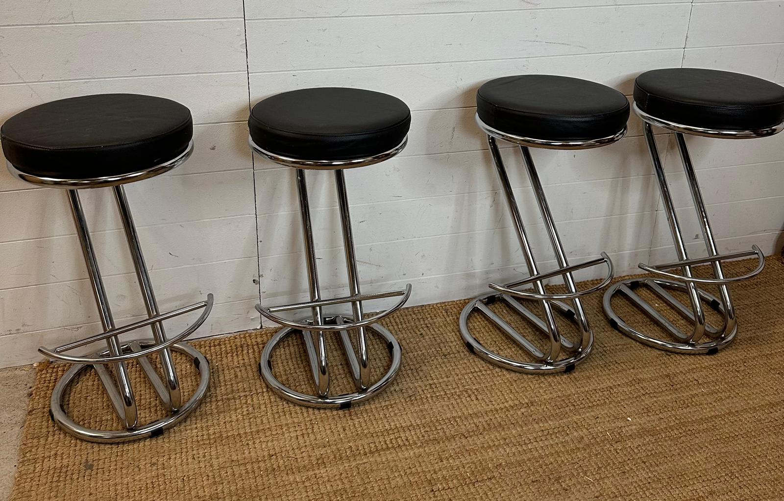 Four black faux leather bar stools on chrome bases (H69cm)