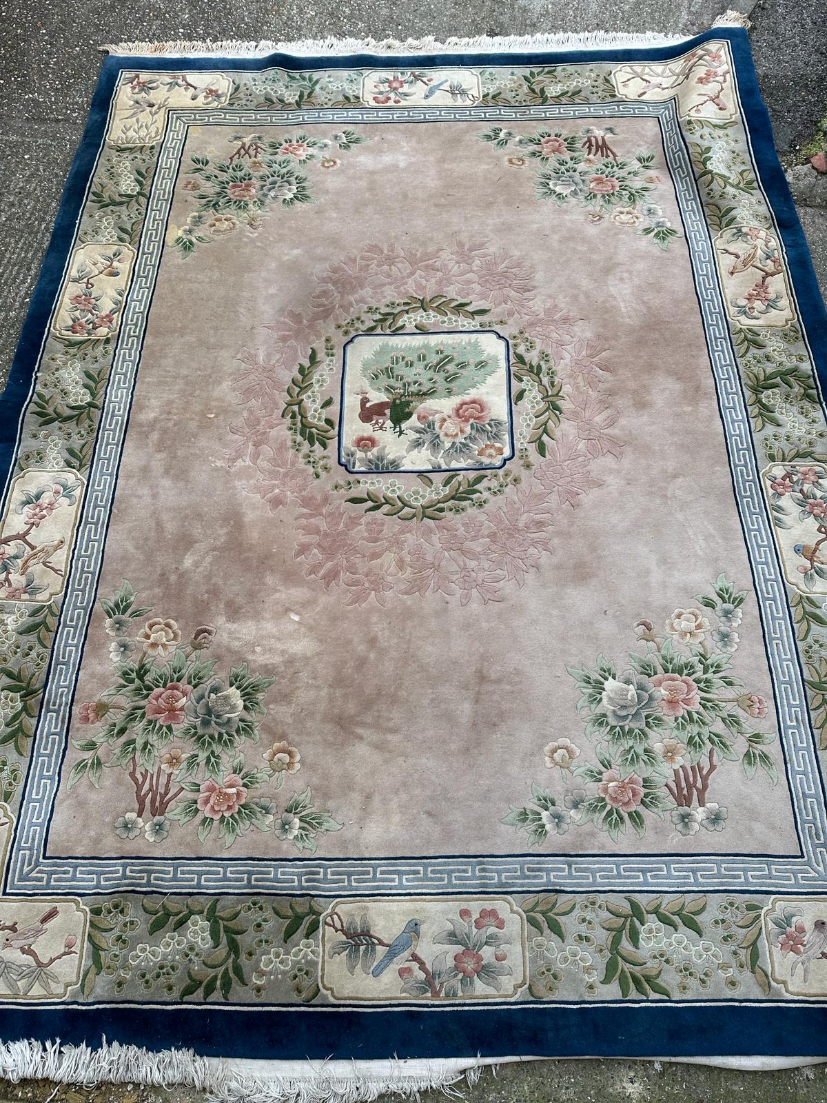 A large Chinese style wool rug/carpet with pink grounds and geometric boarder 390cm x 270cm