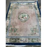 A large Chinese style wool rug/carpet with pink grounds and geometric boarder 390cm x 270cm