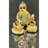 Three 9ct gold charms with a crystal bodied owl with ruby eys, along with a spinner and a swan
