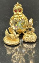 Three 9ct gold charms with a crystal bodied owl with ruby eys, along with a spinner and a swan