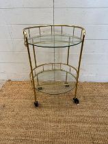 A glass and brass effect drinks trolly with galleried top (H60cm Dia38cm)