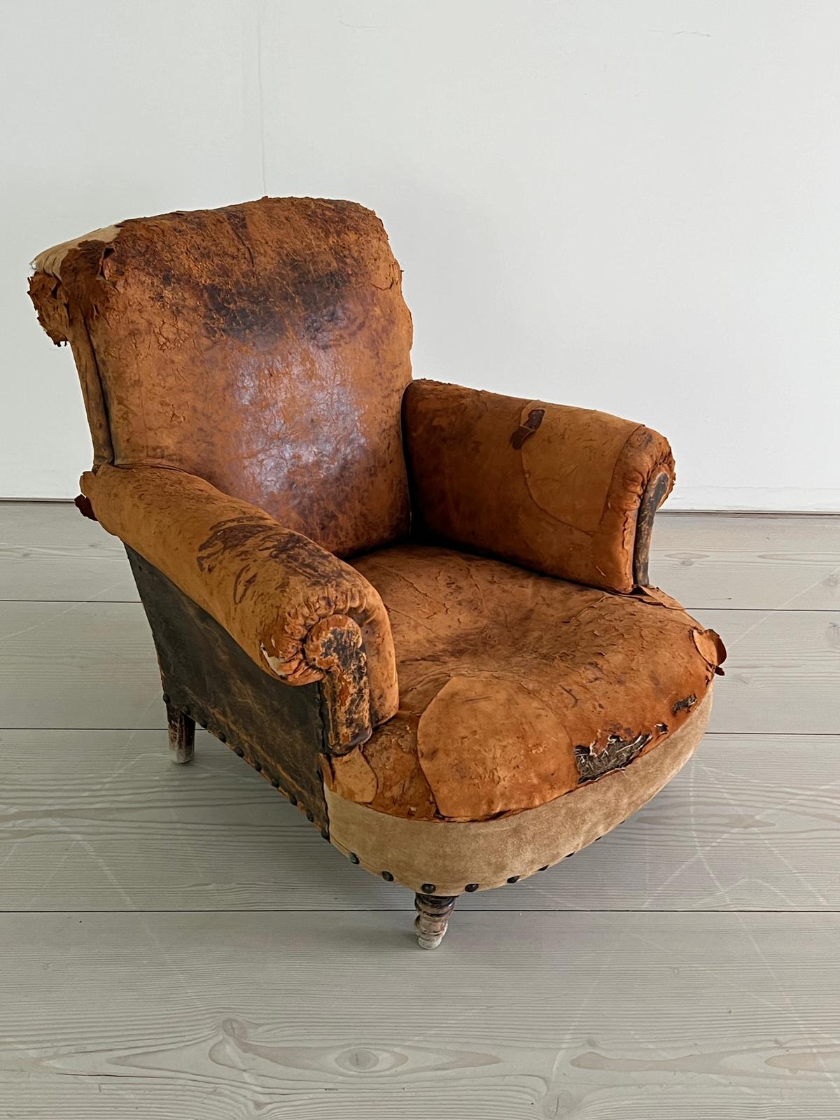 An antique leather club chair in a distresses manner (H84cm W87cm D79cm SH32cm