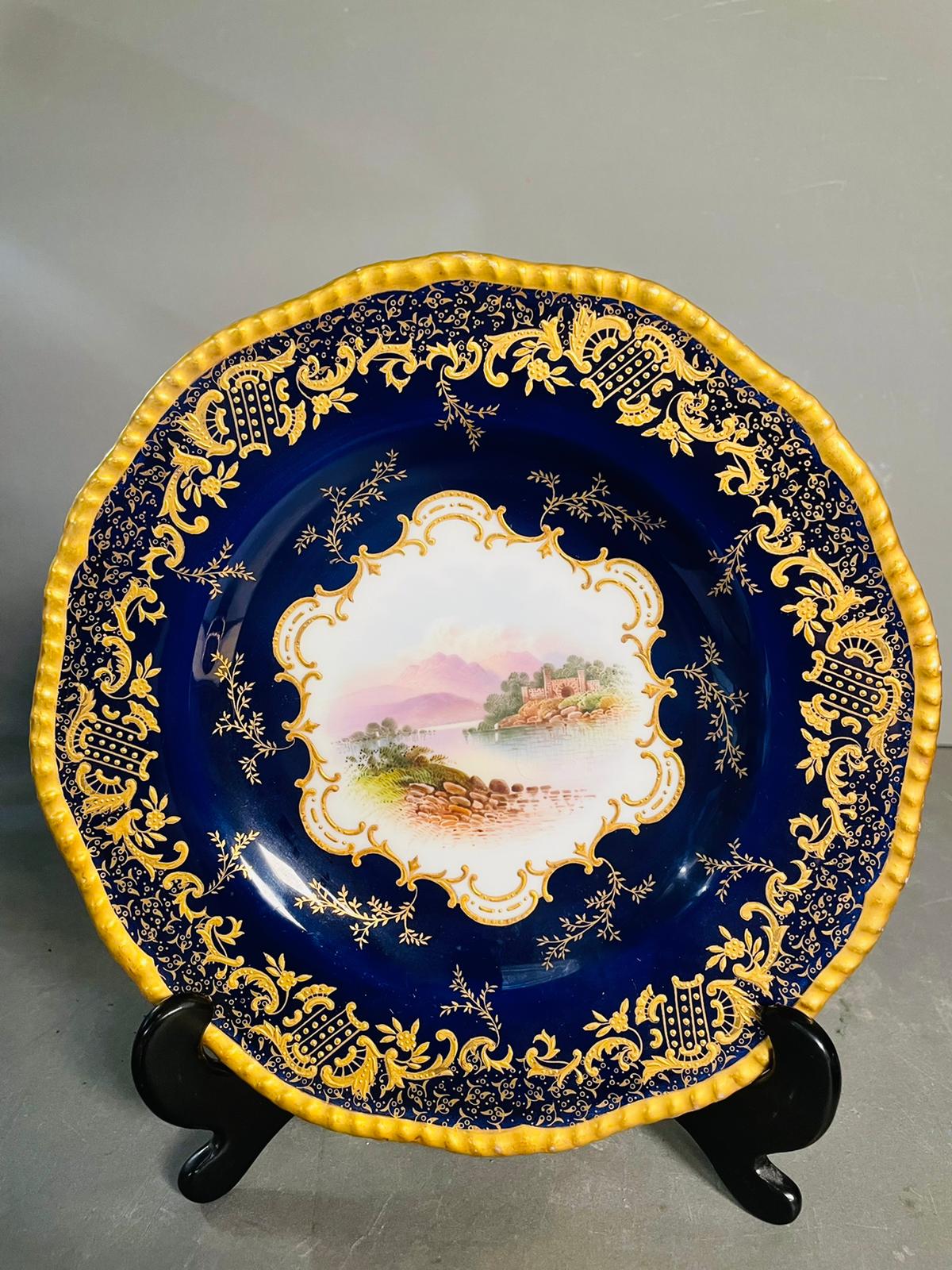 A selection of five early 20th century Coalport hand painted plates with blue grounds, under an acid