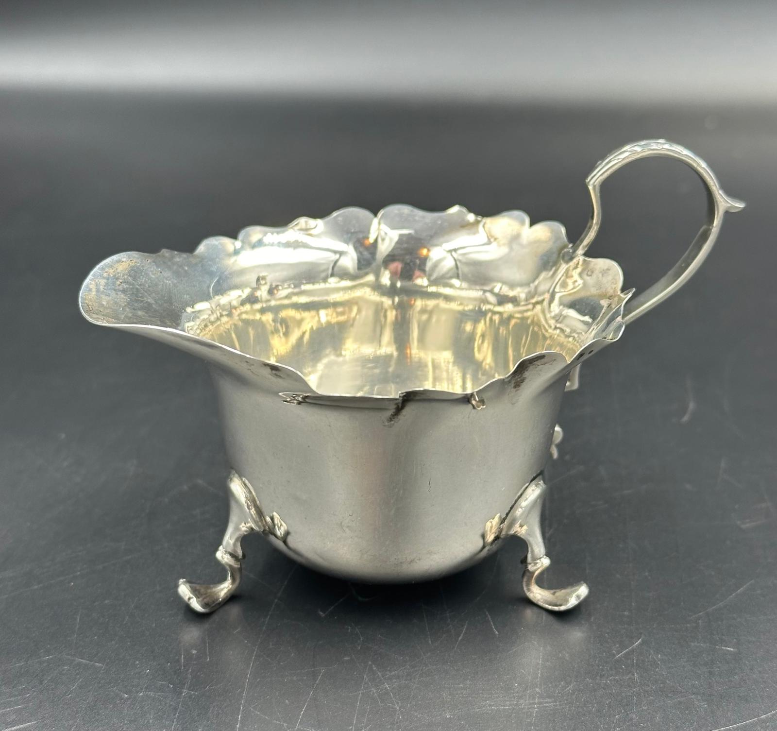 A silver milk jug on three feet by James Aitchison, London 1908, approximate total weight 50g.