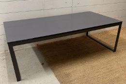 A grey rectangular coffee table on a wrought iron painted base with glass top