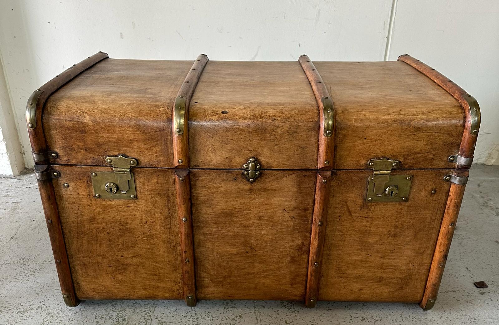 A vintage wooden banded steamer trunk with brass fittings and leather strap handles to ends