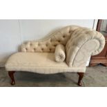 A small button back chaise lounge, upholstered in a cream floral pattern