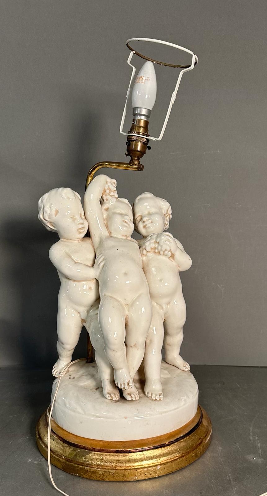 A white ceramic figural cherub table lamp on gold painted base