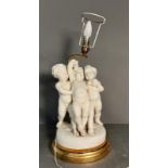 A white ceramic figural cherub table lamp on gold painted base