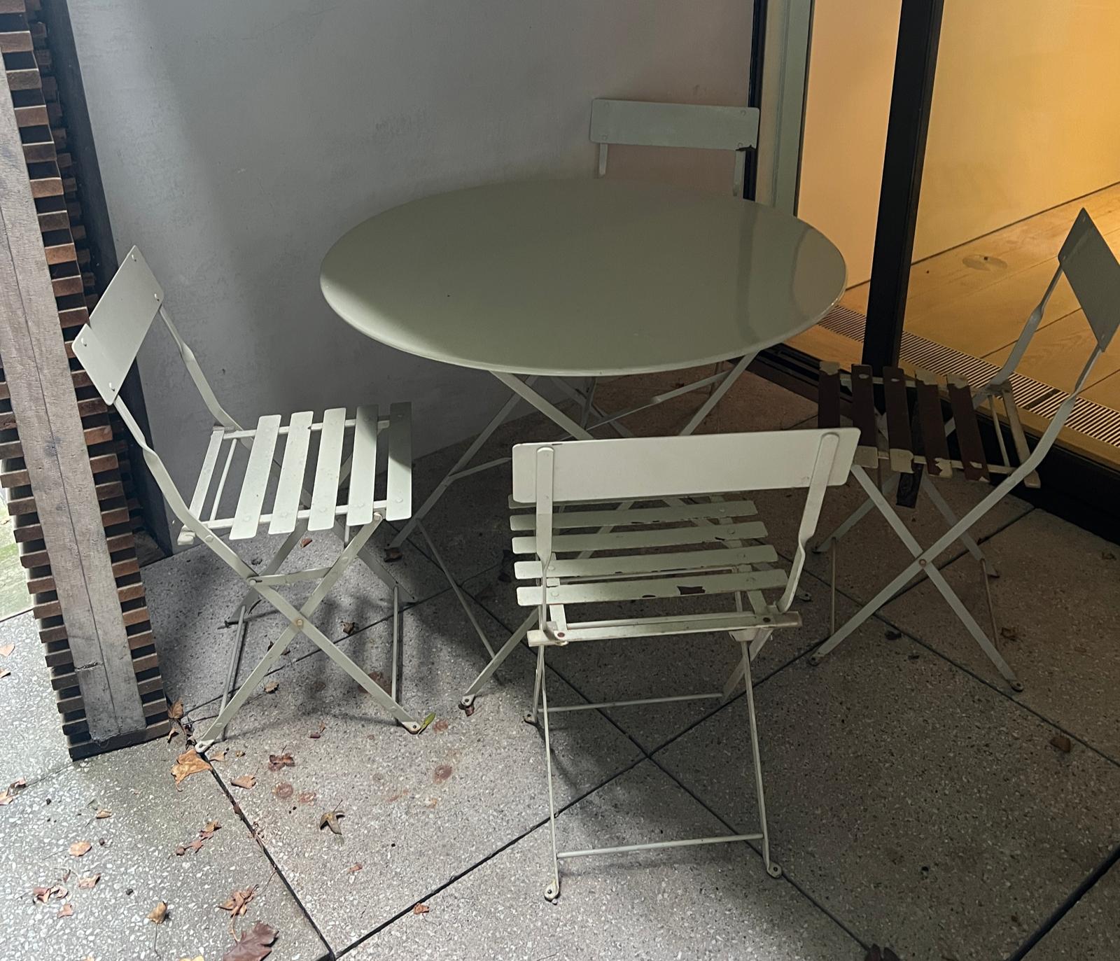 A metal bistro set comprising of a table and four folding chairs (H74cm Dia97cm)