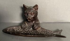 A bronze of a cat holding a fish possibly a pin tray or trinket dish