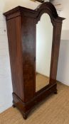 A Victorian mahogany wardrobe with arched hood, the panelled inlaid sides with centre mirrored doors