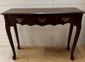 A three drawer magnolia console table with brass drop down handles (H69cm W92cm D31cm)