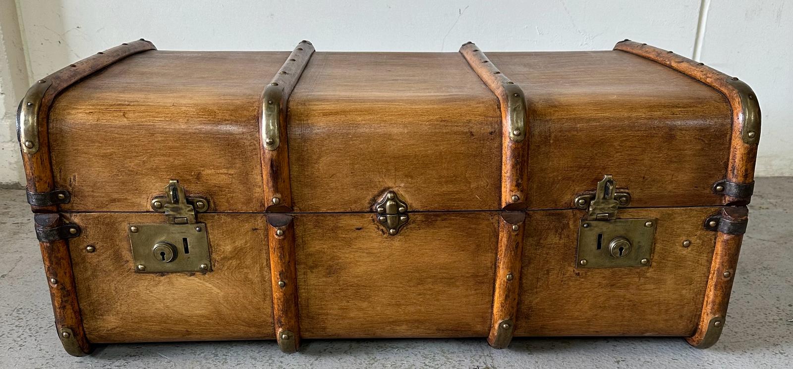 A vintage wooden banded steamer trunk with brass fittings, opening to single shelf with stripped