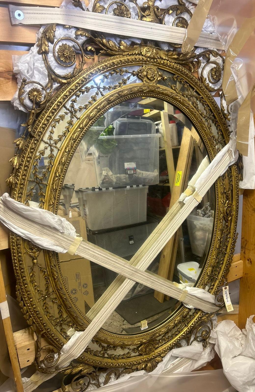 A large George lll gilt wood oval mirror. The frame with urn cresting and floral and foliate scrolls