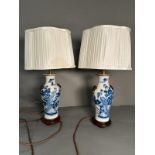A pair of Chinese blue and white table lamps in a floral bird pattern with foo dogs to side