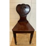 A mahogany carved hall chair c 1820, the shaped back carved with reeded scrolls. AF