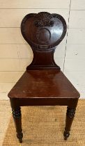 A mahogany carved hall chair c 1820, the shaped back carved with reeded scrolls. AF