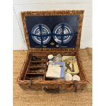 A wicker picnic basket comprising of blue and white plates, cutlery, thermos and plastic glasses