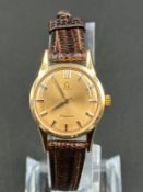 Gold Omega Ladymatic wristwatch on a brown leather strap. 26mm case. Plexi glass. Swiss Gold