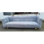A contemporary four seater upholstered sofa in grey on brass ball feet 230cm x 86cm