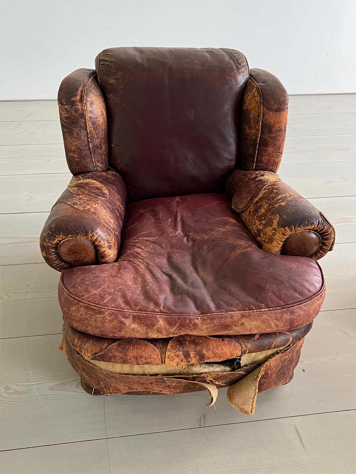 An antique leather club chair in a distressed manner (H84cm W97cm SH37cm)