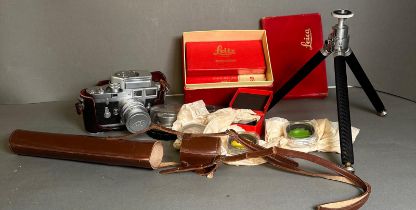 A vintage Leica camera along with a large number of accessories, including tripod