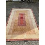 A beige ground wool rug in red, brown and orange 300cm x 210cm