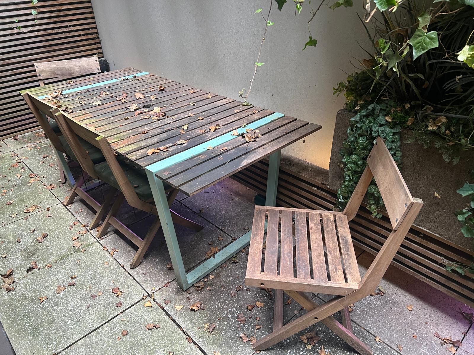 A garden table with four slatted folding chairs, the table with slatted top and aqua metal frame (