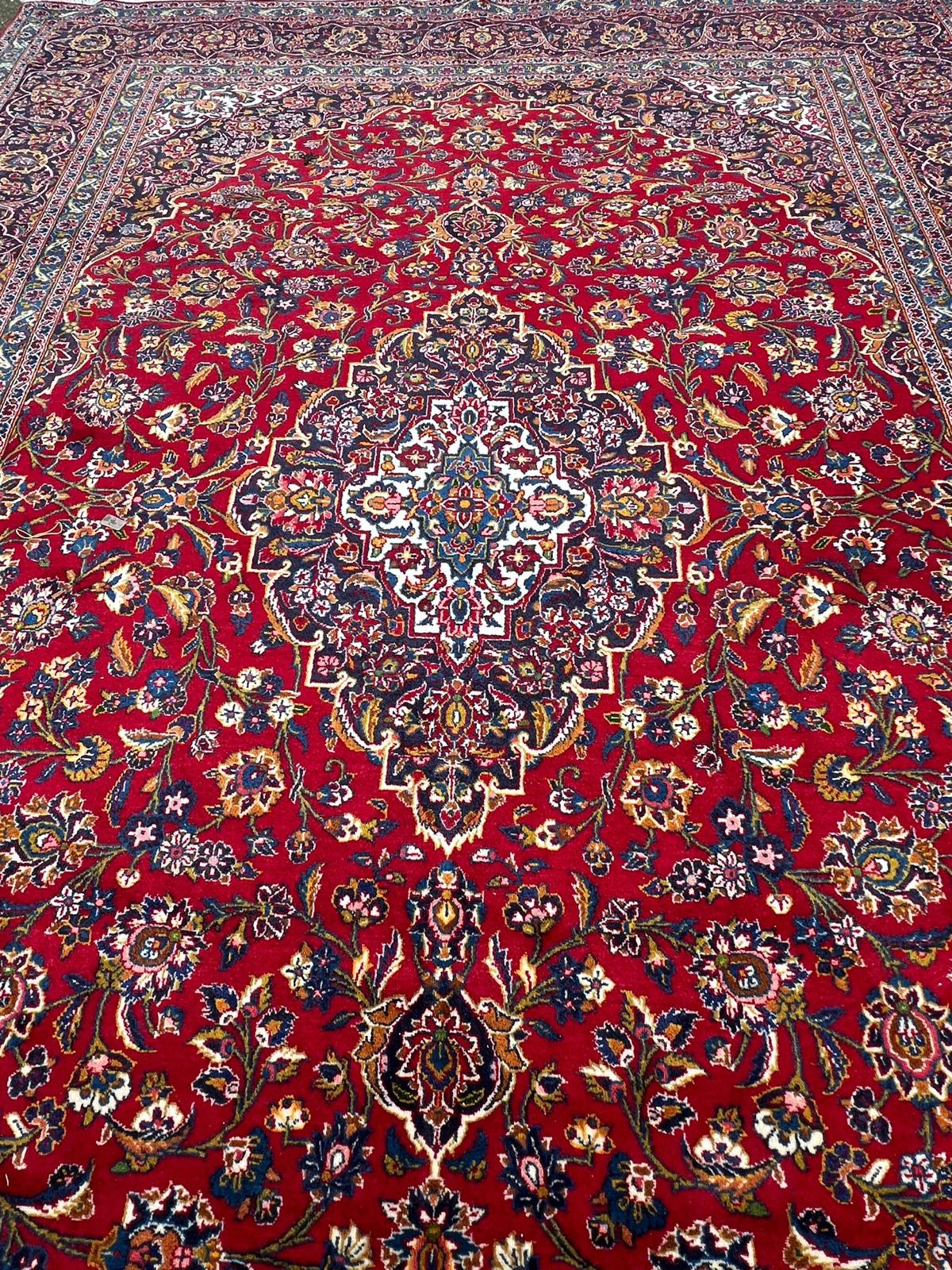 A hand knotted wool Kashan rug, rich red background with central medallion and elaborate - Image 2 of 8