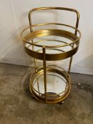 A mirrored drinks trolly, two tier on castors (H80cm Dia40cm)
